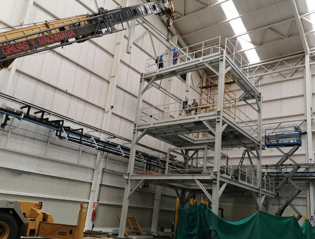 Instalación de estructura metálica de varios niveles con grúa industrial en planta